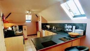 Una cocina compacta con una isla central, taburetes de bar, un ventanal y un pequeño comedor.