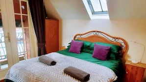 Un dormitorio con cama, tragaluz, armario y mesita de noche.