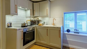 A modern kitchen with a built-in oven, a microwave, and a sink with a gold faucet. - Rural romantic getaway for two. (Neath)