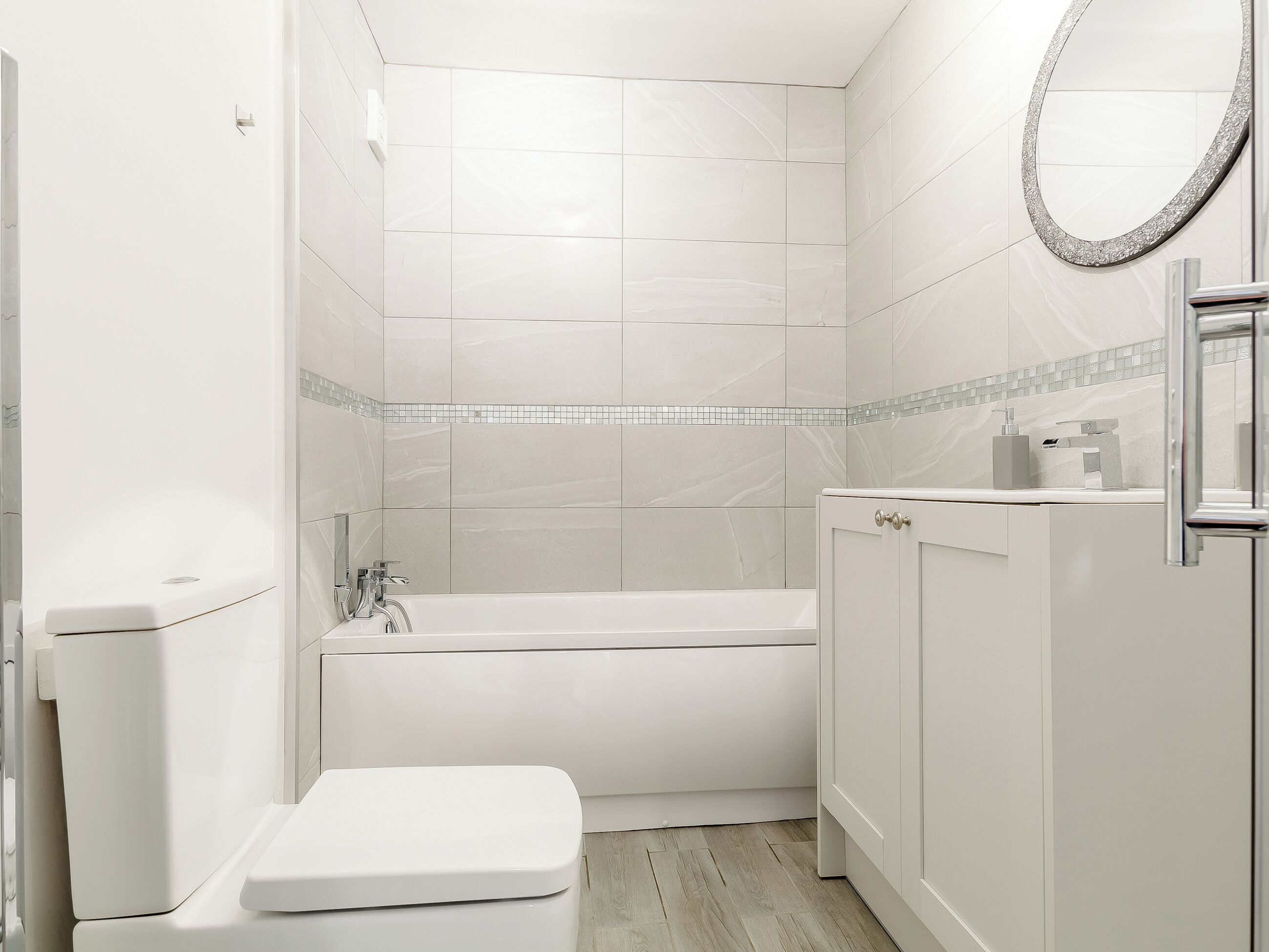 A bathroom with a toilet, a bathtub, and a sink with a mirror.