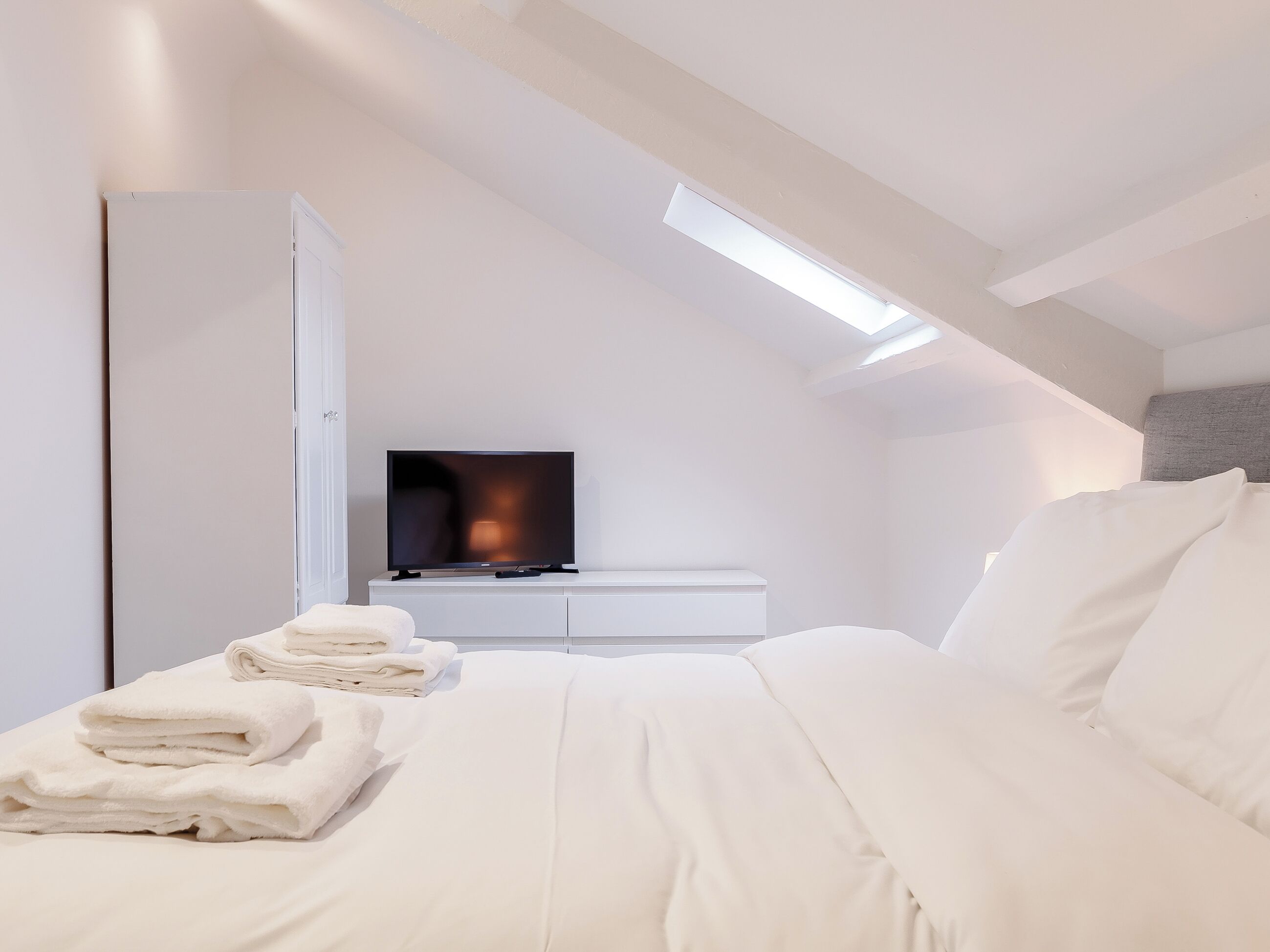 Ein modernes Schlafzimmer mit einem Bett, einem Fernseher und einem Kleiderschrank.