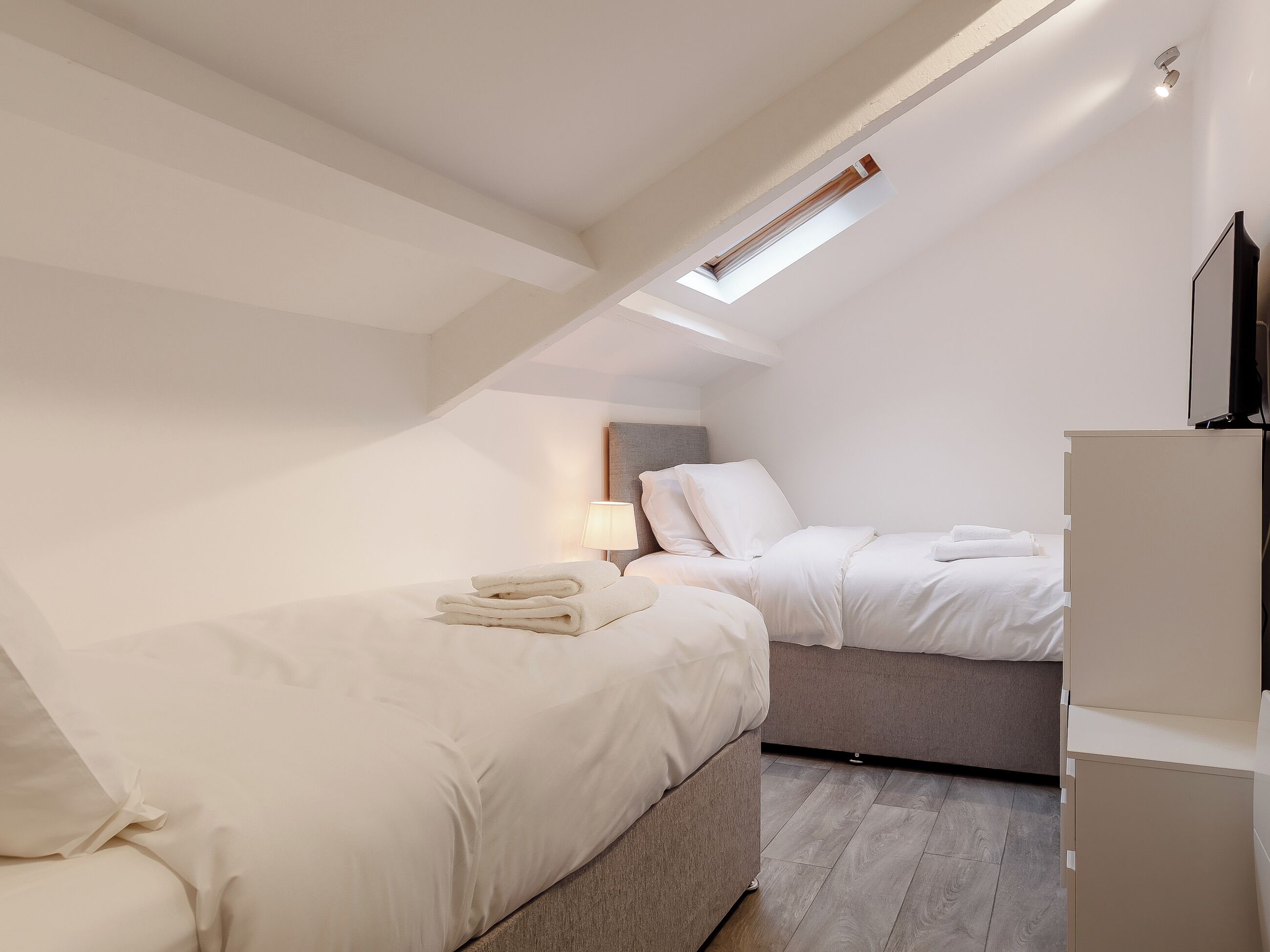 Une chambre avec deux lits, un bureau et une télévision.