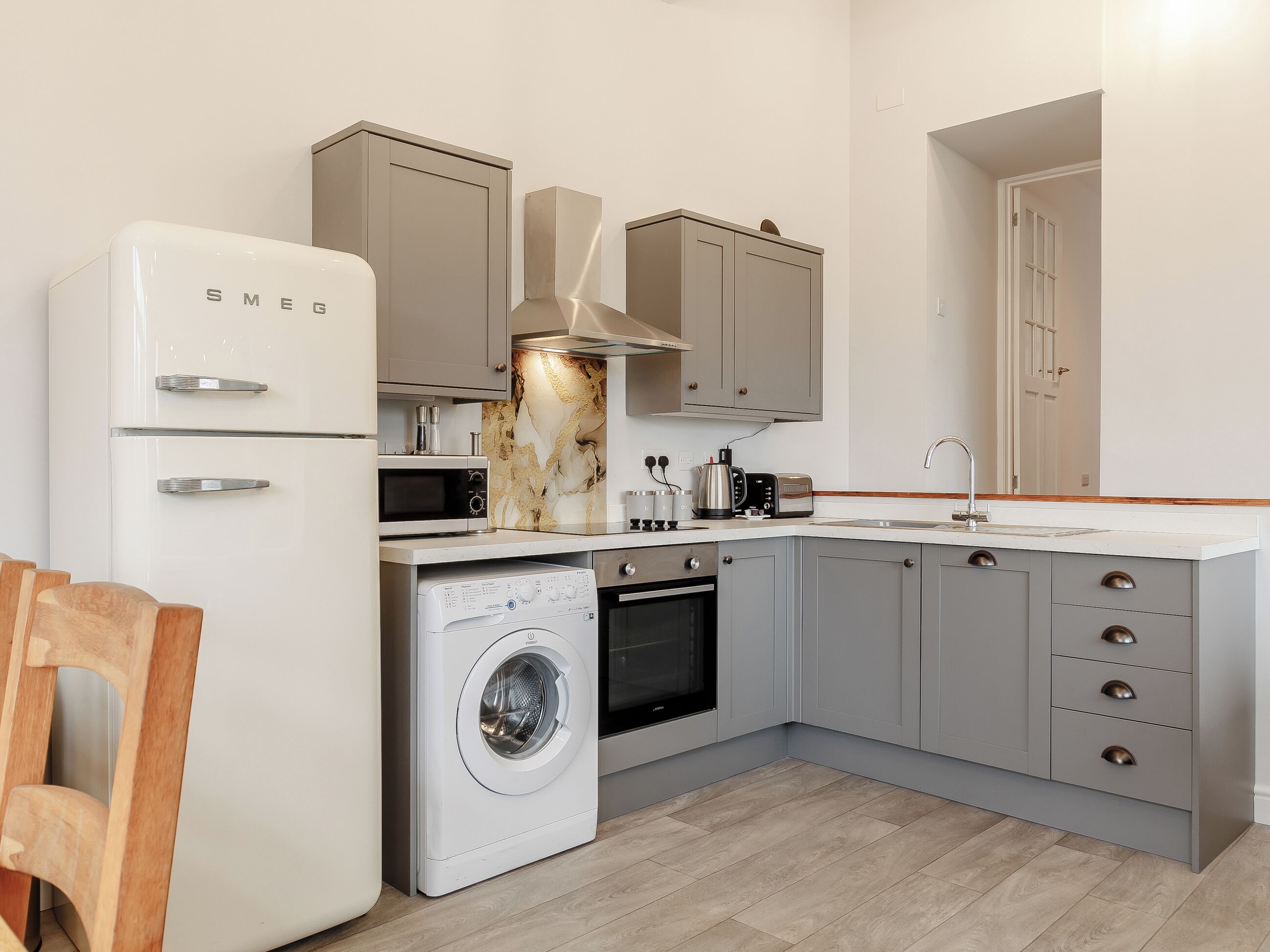 A compact kitchen with a washing machine, microwave, oven, and a sink.