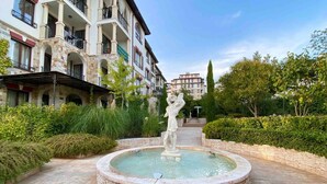 A courtyard with a fountain, stone walls, and a statue. - New Modern Studio - Artur, Sveti Vlas - Apartello (Sveti Vlas)