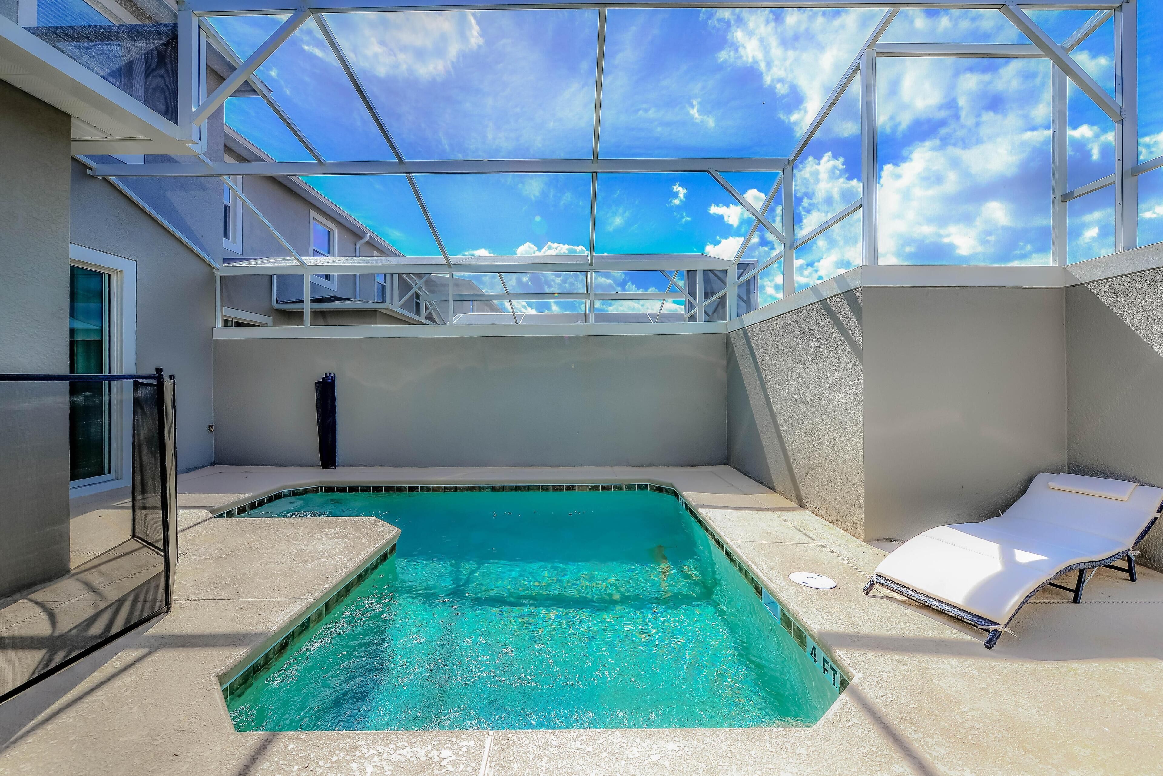 A rooftop swimming pool with a glass ceiling, a lounge chair, and a view of the sky.
