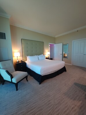 A hotel room with a large bed, two bedside tables, a chair, and a wardrobe. - SuitestayLV~1BR Corner PH Suite/Balcony 31st Floor (Las Vegas)