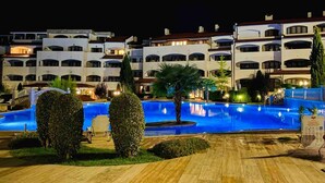 Ett hotell med flera balkonger, en swimmingpool och välskött trädgård.