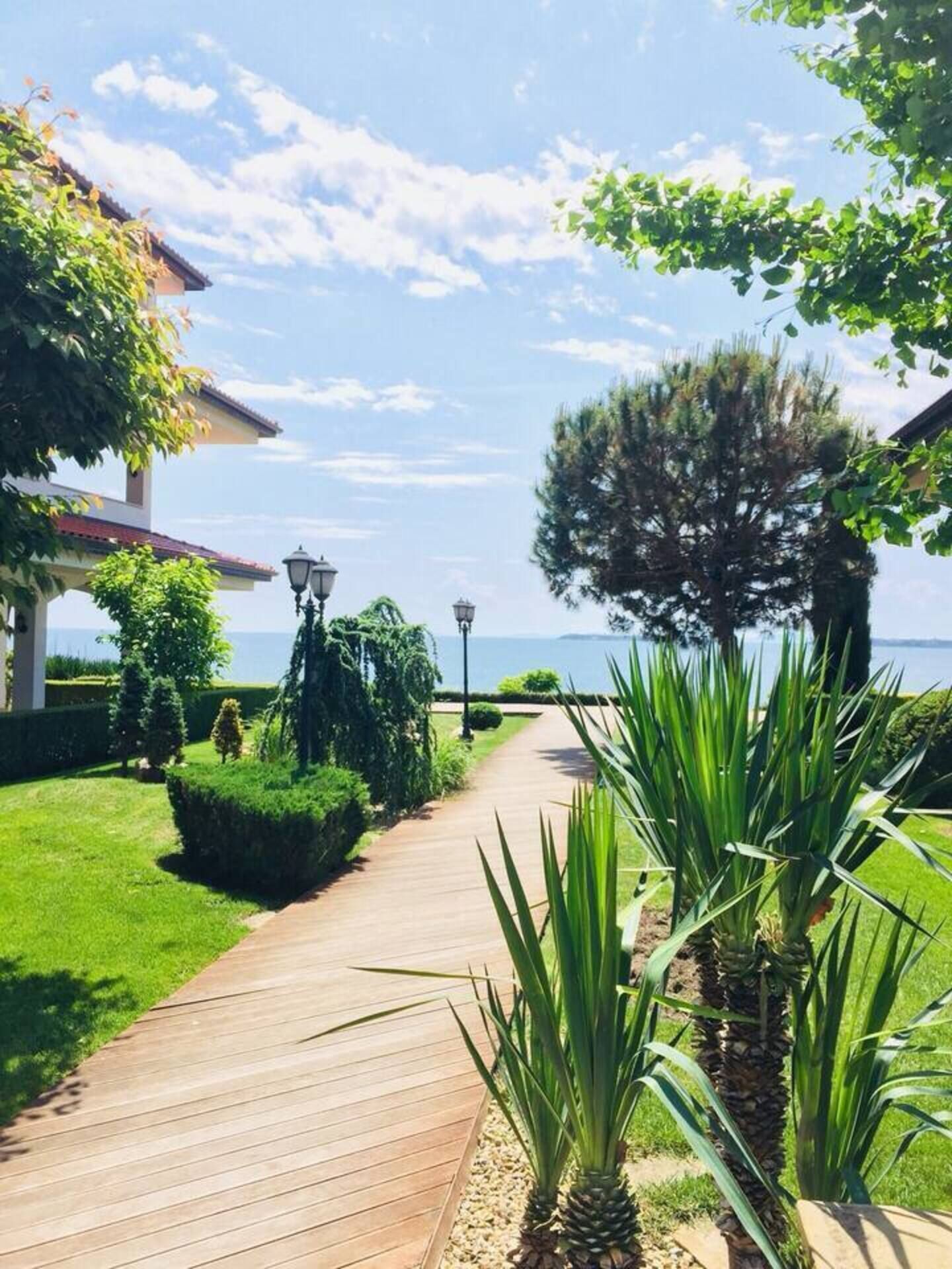A wooden pathway leading to a building with a view of the sea.