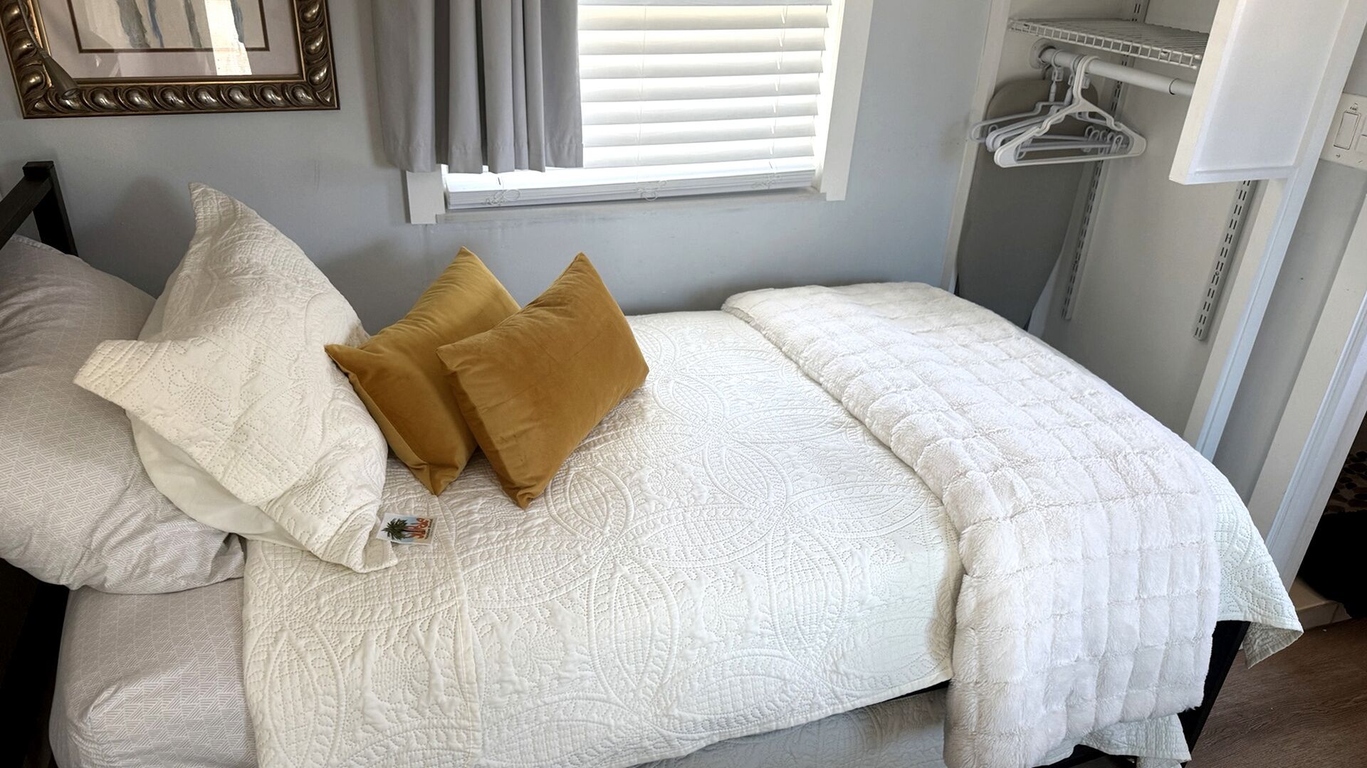 Un lit bien fait, avec une couette blanche, deux oreillers et une couverture.