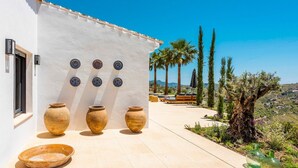 Een wit gebouw met grote terracotta potten, een terras met zitplaatsen en uitzicht op het platteland.