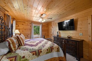 Habitación con paneles de madera, una cama, un aparador y un televisor.