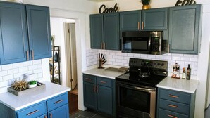 Una cocina moderna con armarios color turquesa, estufa negra y un microondas.