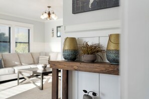 A living room with a wooden coffee table, a sofa, and a decorative shelf with vases and a plant. - The Modern Vintage – Spacious 4BR Family Home Walk to Beach Near Redwoods (Crescent City)