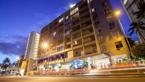 Ein mehrstöckiges Hotel mit Balkonen, einem Restaurant im Erdgeschoss und einem gut beleuchteten Eingang.