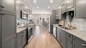 A modern kitchen with grey cabinets, stainless steel appliances, granite countertops, and a central island with seating. - Lovely Mountain Views Gatlinburg atop ChaletVillage HotTub GameRm Pets Sleeps10 (Gatlinburg)