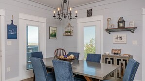 A dining area with a large table, six upholstered chairs, a chandelier, and various wall decorations. - Lovely Mountain Views Gatlinburg atop ChaletVillage HotTub GameRm Pets Sleeps10 (Gatlinburg)