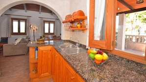 A kitchen with granite countertops, wooden cabinets, a built-in sink, and a fruit bowl.