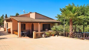 A two-story house with a tiled roof, a covered patio, and a fenced garden area.