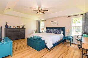 A bedroom with a bed, a desk, a dresser, and a ceiling fan.