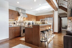 A modern kitchen with wooden cabinets, stainless steel appliances, and a central island with bar stools. - Charlie Rentz: Bachelor Gulch Ski-In/Out, Sleeps 12, Ritz Pool + Hot Tub Access, 2 King Suites (Avon)