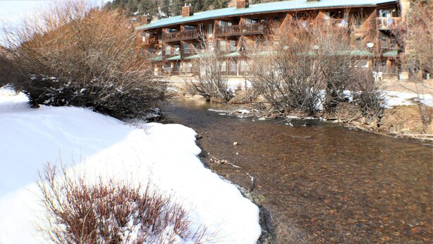 Une rivière qui traverse un paysage enneigé, avec un chalet visible au loin.