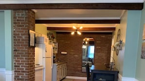 A spacious kitchen with wooden floors, a brick accent wall, and a dining area with a small round table.