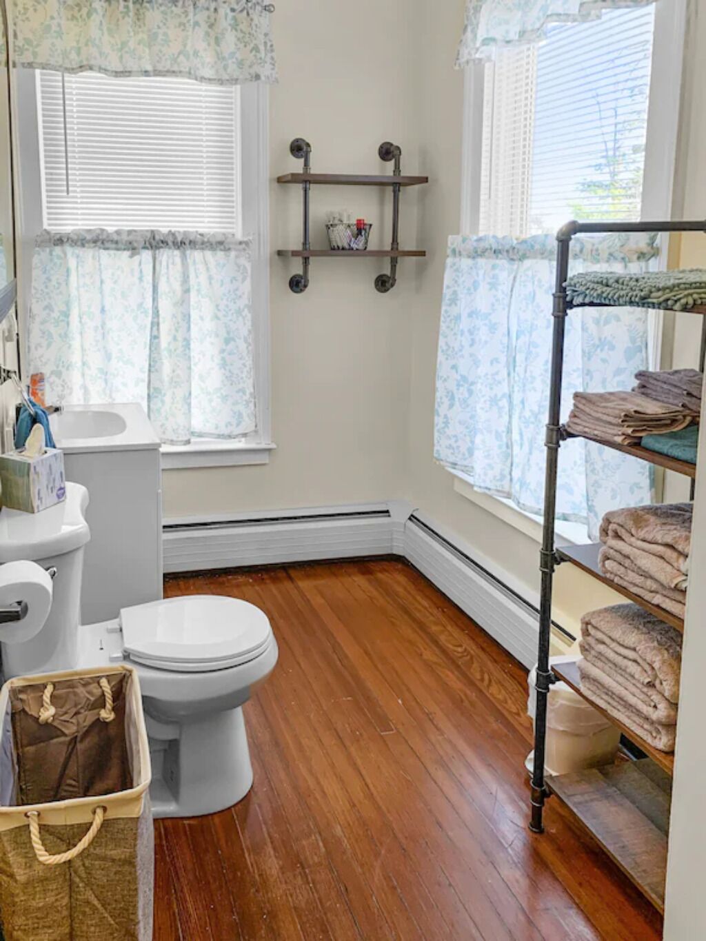 Une petite salle de bain avec des toilettes, une étagère avec des serviettes et un panier.