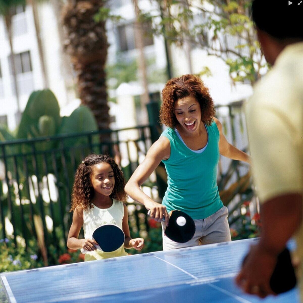 A group of people playing table tennis outdoors.