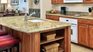 Una cocina con armarios de madera, encimera de granito, microondas y lavavajillas.