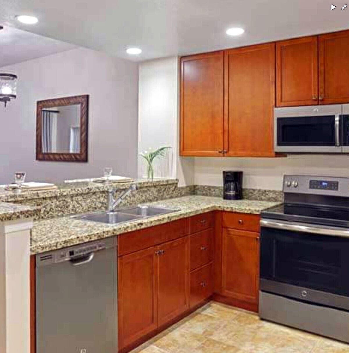 A kitchen with granite countertops, wooden cabinets, a dishwasher, a microwave, and an oven.