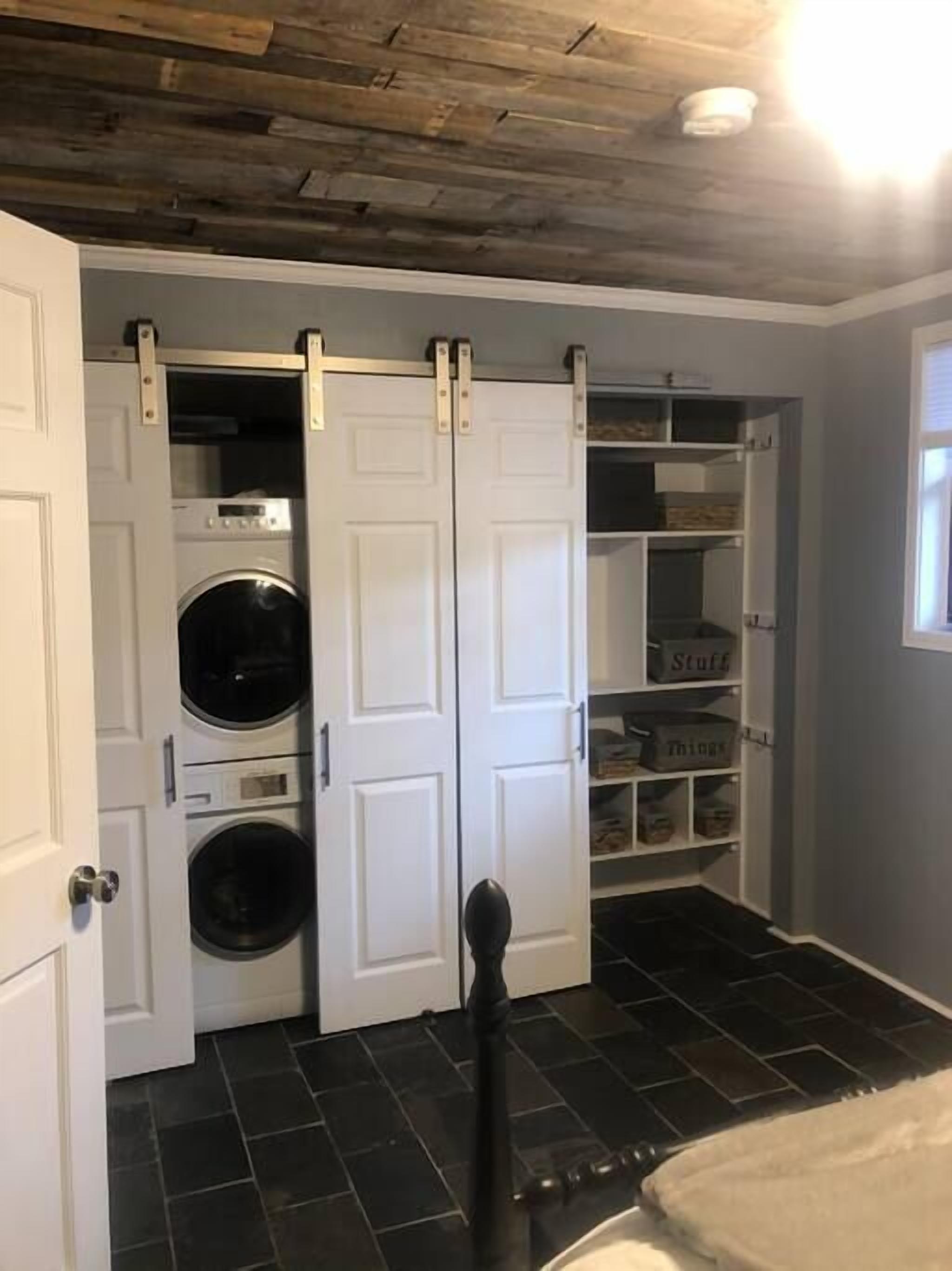 Une buanderie équipée d’un lave-linge, d’un sèche-linge et d’un espace de rangement avec des bacs étiquetés.