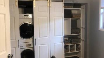 Une buanderie équipée d’un lave-linge, d’un sèche-linge et d’un espace de rangement avec des bacs étiquetés.