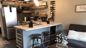 A modern kitchen with a central island, bar stools, a coffee machine, and a wine rack. - Completely Remodeled-- 1/1 just 2 blocks from the base! (Angel Fire)
