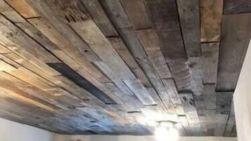 A room with a sloped ceiling made of wooden planks, a window, and a door.