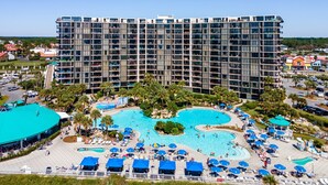 Un hôtel de grande hauteur doté de nombreux balcons, d’une piscine centrale et d’un espace piscine aménagé avec des chaises longues et des parasols.