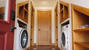 Un cuarto de lavandería con dos lavadoras, armarios de madera y una puerta de madera.
