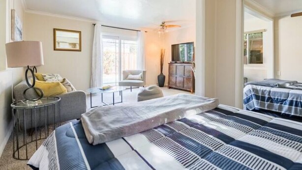 A bedroom with a bed, a chair, a TV, and a window. - Modern poolside house with AC Downtown Mountain View! (Mountain View)
