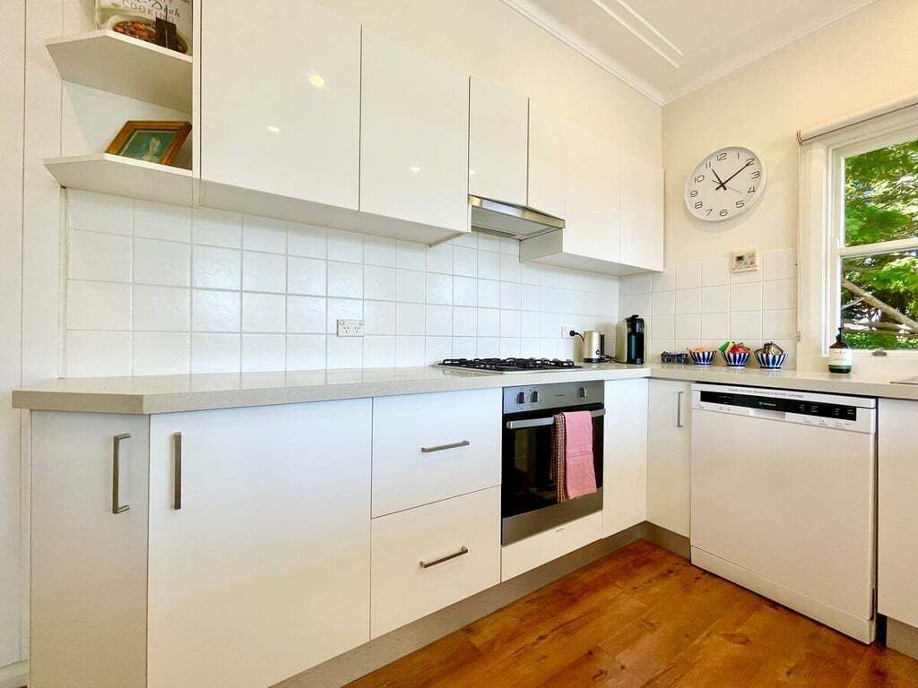 Une cuisine avec des meubles blancs, une cuisinière, un four et un lave-vaisselle.