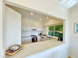 Eine moderne Küche mit weißen Schränken, einem großen Fenster und einer Arbeitsplatte mit einer Tablett.