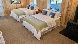 Quarto com duas camas, paredes de madeira, um relógio, uma janela e uma lareira.