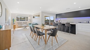 A modern kitchen with a central island, a dining area with a table and chairs, and a living space with a sofa and chairs.