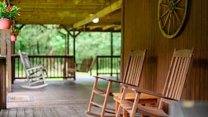 Un portico in legno con sedie a dondolo e un tavolo di legno.