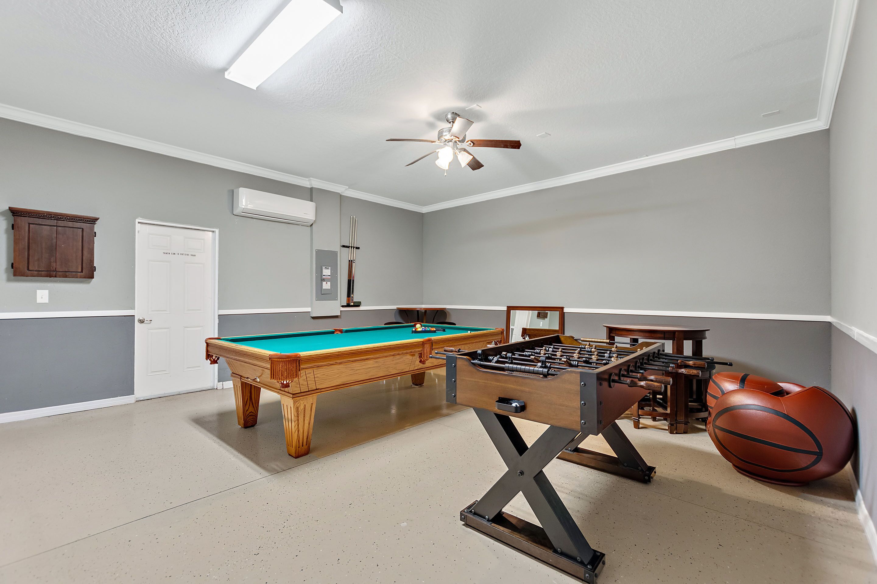 A room with a pool table, foosball table, and a basketball.