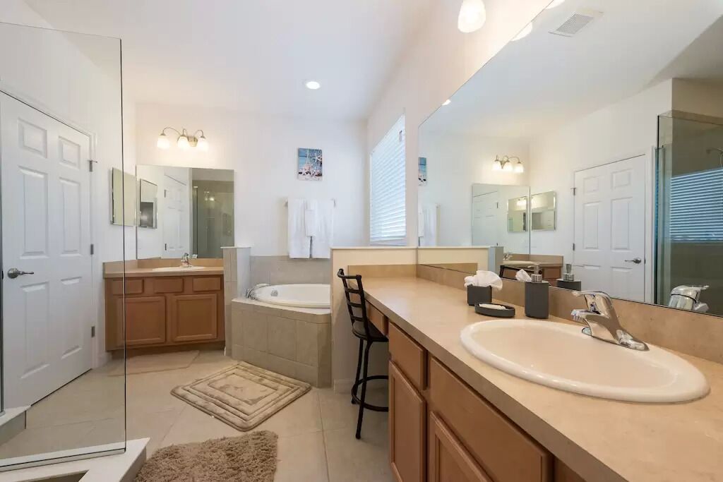 Une salle de bain moderne avec un grand miroir, une baignoire, un lavabo et un espace douche.