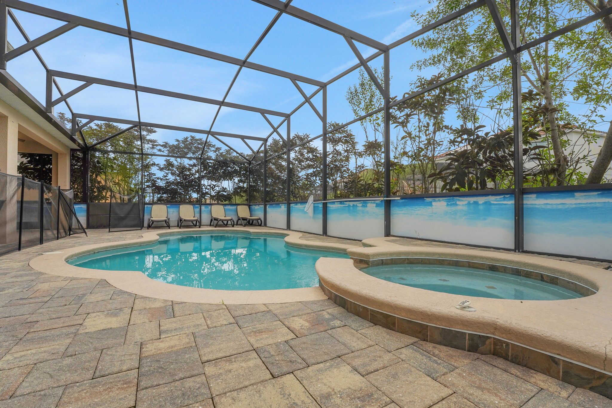 An indoor swimming pool with a glass enclosure, lounge chairs, and a hot tub.