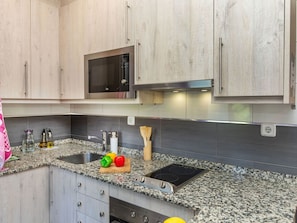 Een keuken met granieten aanrechtbladen, roestvrijstalen apparatuur en houten keukenkastjes.