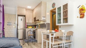 Una cocina funcional con comedor, un refrigerador y una pequeña mesa con sillas.