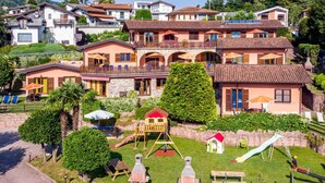 A residential area with multiple houses, a playground, and a paved walkway. - Nice apartment for 5 guests with WIFI, pool, A/C and TV (Luino)