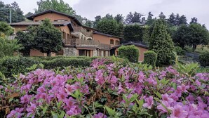 Una casa a due piani con un balcone e un giardino pieno di fiori rosa.