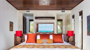 A spacious bedroom with a large bed, two bedside lamps, and a television. - Beach Kandi 15% off stays in Fall 2026 | Beach Front - Located in  Magnificent Grace Bay with House Cleaning Included (Providenciales)